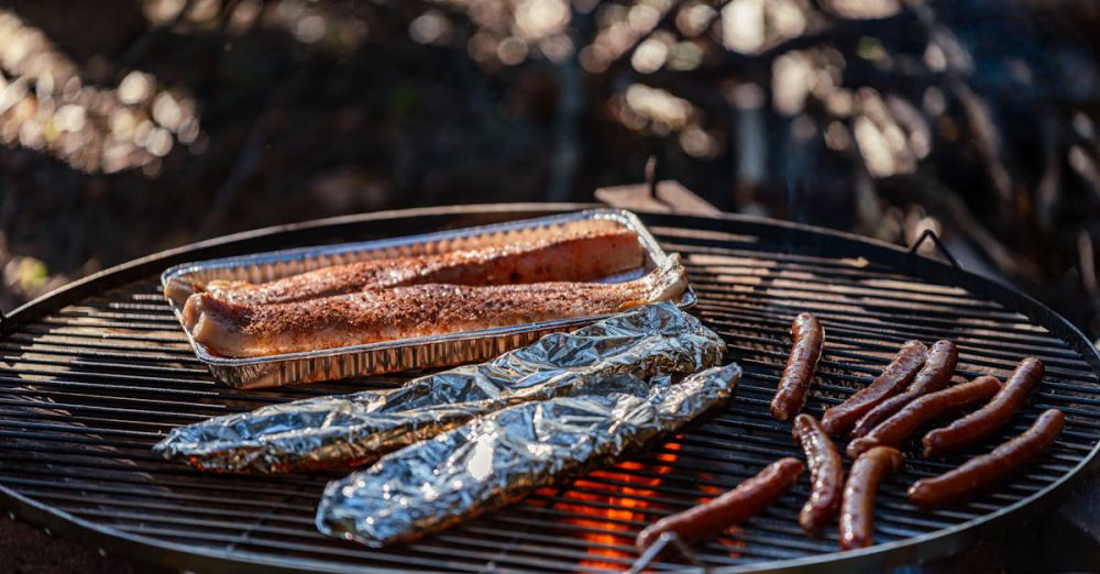 Budget Camping - Grilled food including sausages and fish cooked over an open outdoor fire.