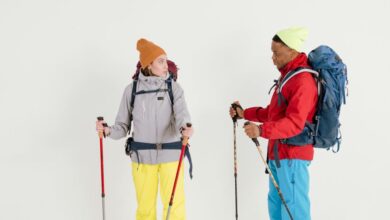 Hiking - Two hikers in winter clothing with backpacks and trekking poles in a studio setting.