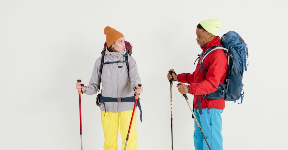 Hiking - Two hikers in winter clothing with backpacks and trekking poles in a studio setting.