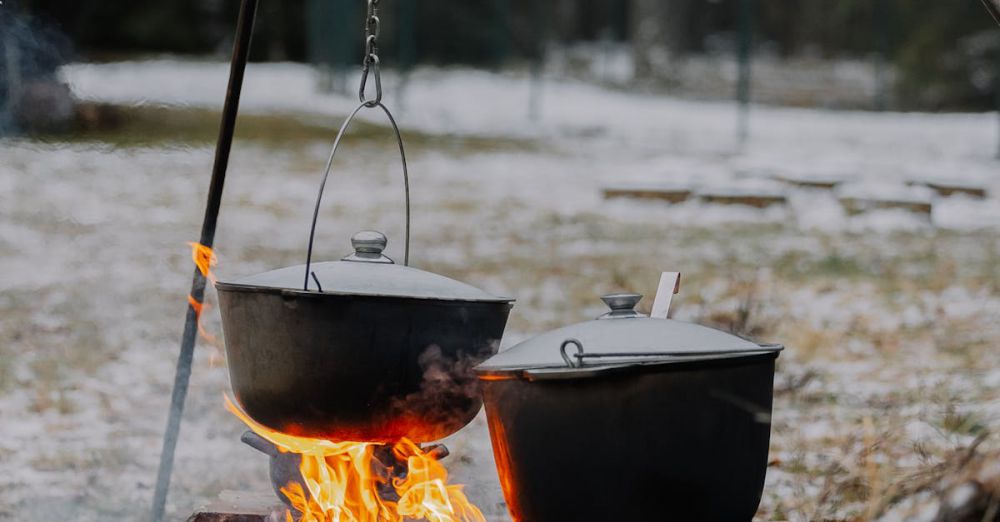 Winter Camping - A cozy winter scene showing outdoor cooking over an open fire with snow all around.