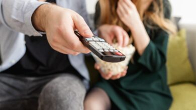 Remote - A couple enjoying a relaxing movie night, sitting on a sofa with popcorn and a TV remote.