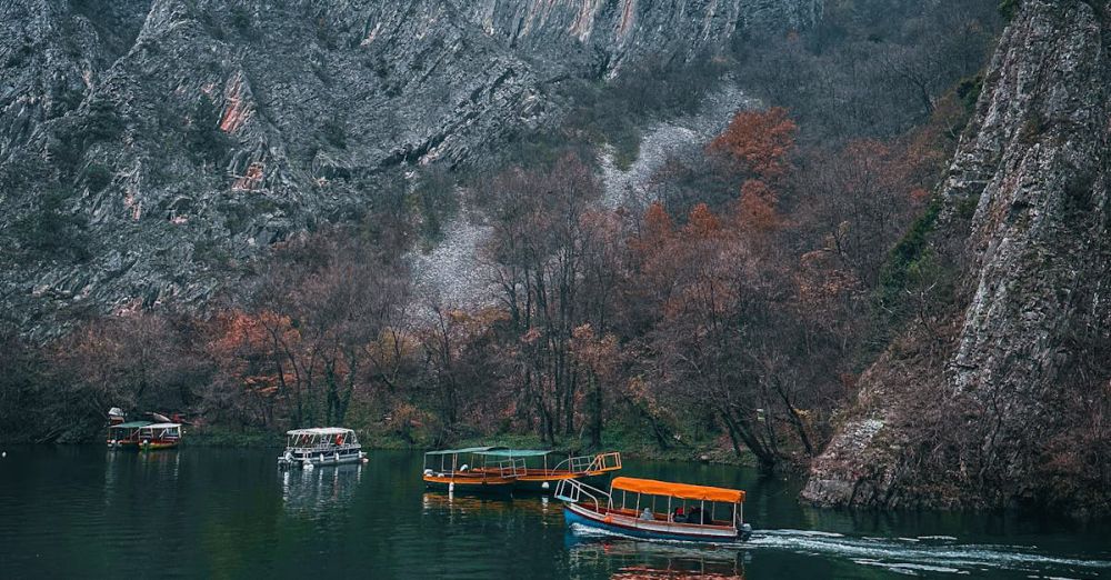 Popular Campsites - Boats cruising Matka Canyon's serene waters with majestic limestone cliffs and autumn foliage.