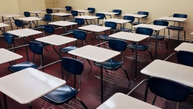 Desks - An indoor view of a modern, clean classroom with rows of empty desks and chairs.