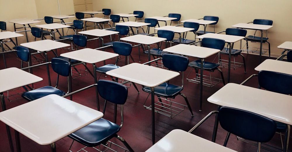 Desks - An indoor view of a modern, clean classroom with rows of empty desks and chairs.