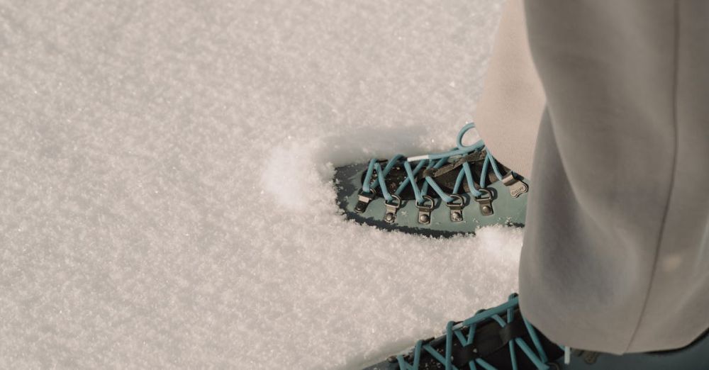 Hiking - Two pairs of hiking boots with colorful laces on pristine winter snow. Perfect for adventure and travel themes.