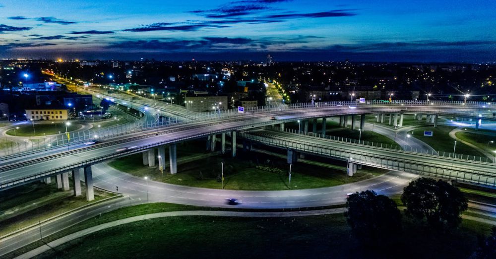 Transportation - A dramatic cityscape featuring a modern flyover lit by vibrant city lights at night.