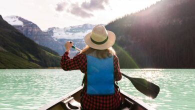 Canoeing - Woman paddles canoe in Lake Louise, enjoying a peaceful summer adventure.