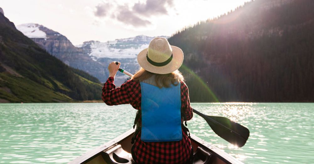 Canoeing - Woman paddles canoe in Lake Louise, enjoying a peaceful summer adventure.