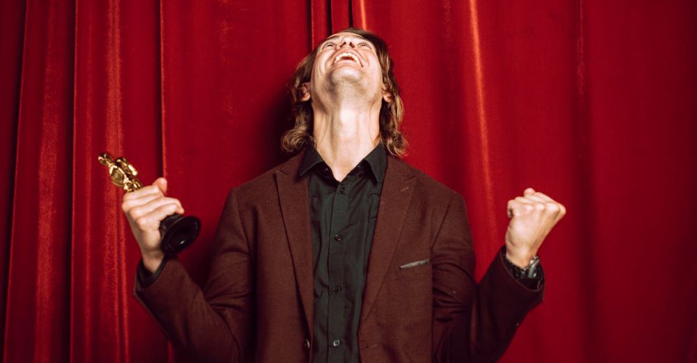 Best Views - Joyful man in a suit celebrates winning an award on stage with a red curtain backdrop.