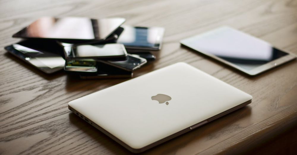 Devices - A variety of modern electronic gadgets, including a laptop and smartphones, on a wooden table.