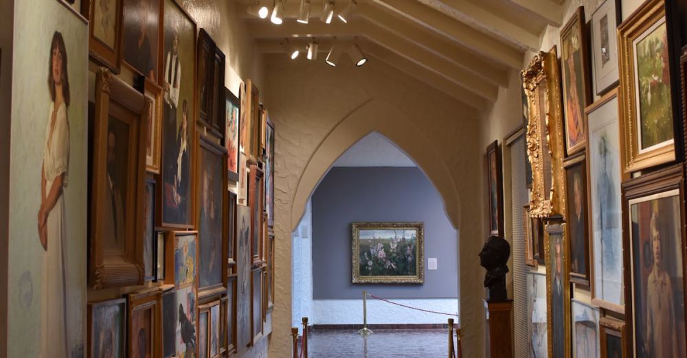 Art Tours - A narrow art gallery corridor showcasing diverse framed paintings under soft lighting.