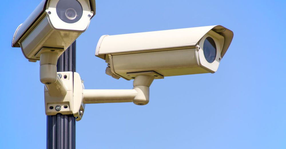 Safety - Outdoor security cameras mounted on a pole against a clear blue sky, ensuring vigilant surveillance.
