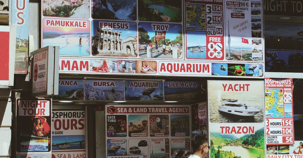 Night Tours - Exterior of a travel agency with colorful tour posters and a passerby on the street during the day.