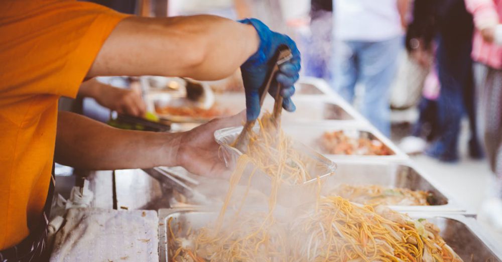 Street Food - A street vendor serving freshly cooked noodles at a bustling outdoor market.