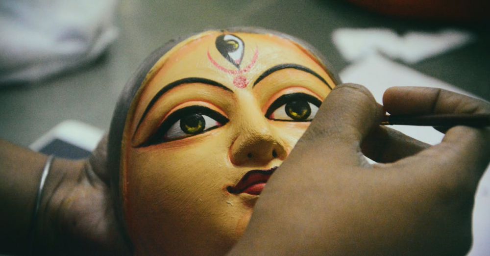 Festival Preparation - Artisan painting a traditional Durga idol mask for the Durga Puja festival.