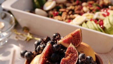 Vegetarian Festivals - High angle of ceramic plate with fresh fruits and berries on table with various snacks