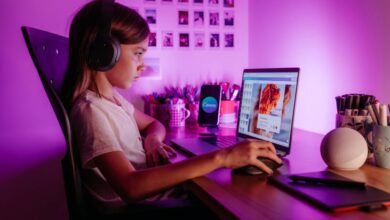 Keyboards - Child focused on laptop wearing headphones at desk with purple lighting. Modern tech scene.