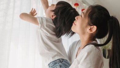 Family Festivals - Asian mother holding son as he reaches for red lanterns in a warm indoor setting.