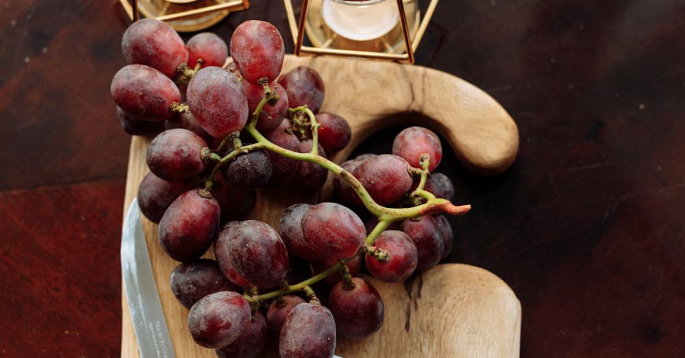 Pairings - A top-view still life of grapes and cheese on a wooden board, exuding rustic elegance.