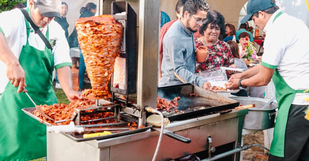 Local Food - Vibrant scene at Mexican street food event featuring tacos al pastor preparation.