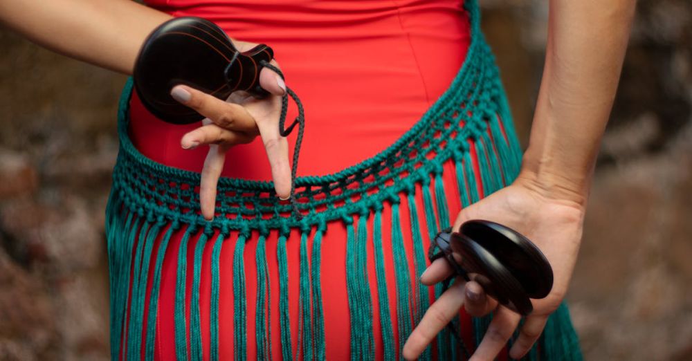 Authentic Festivals - A close-up of a dancer's hands holding castanets with a colorful costume detail.