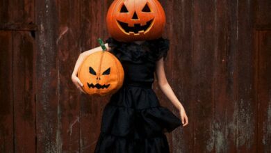 Hidden Festivals - Person in black dress with pumpkin heads at Halloween.