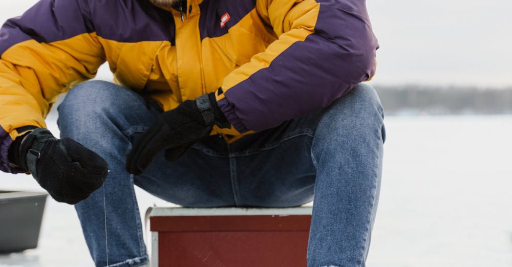 Ice Fishing Locations - A man dressed warmly is ice fishing on a frozen lake during winter, showcasing outdoor recreation.