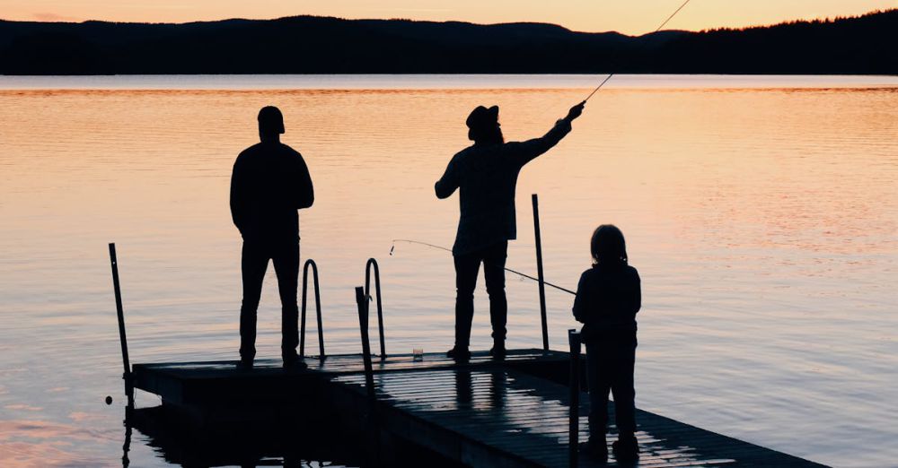 Family Fishing - A serene scene of a family fishing together on a lake dock at sunset, creating silhouettes on the water.