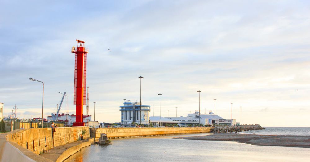 Fishing Guides - Beautiful view of a red lighthouse on a seashore against a calm ocean backdrop at sunset.