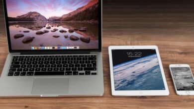 Devices - Modern workspace showcasing Apple laptop, tablet, and smartphone on a wooden desk.