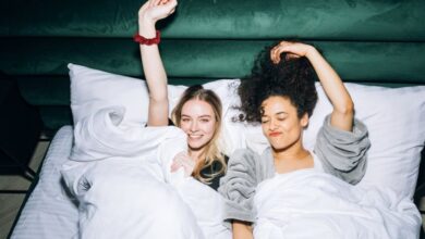 Best Time - Two happy friends enjoying a relaxing time in bed with white linens, exuding joy and friendship.