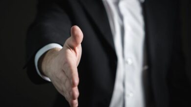 Deals - Close-up of a businessman extending hand for a handshake, symbolizing agreement and partnership.