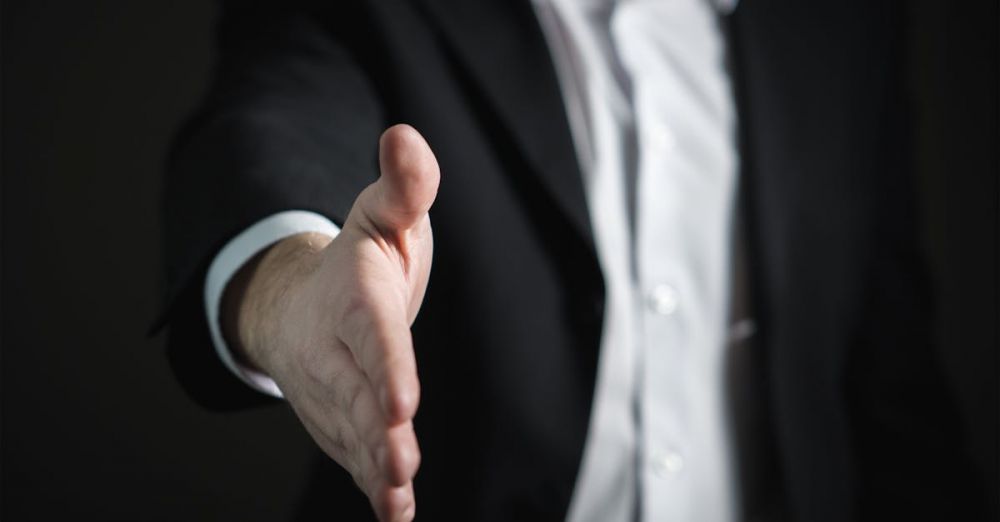 Deals - Close-up of a businessman extending hand for a handshake, symbolizing agreement and partnership.