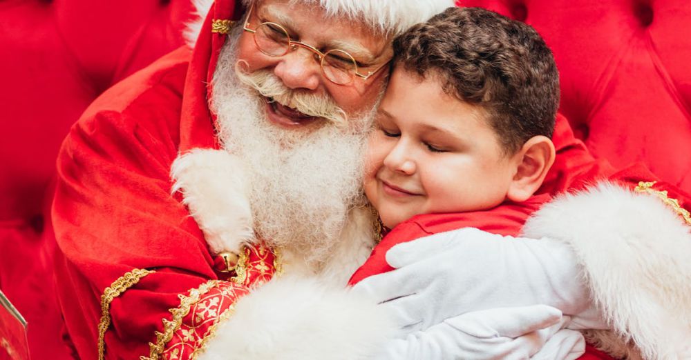 Year-Round Visits - Santa Claus hugs a smiling child on a red chair, capturing a joyful holiday moment.