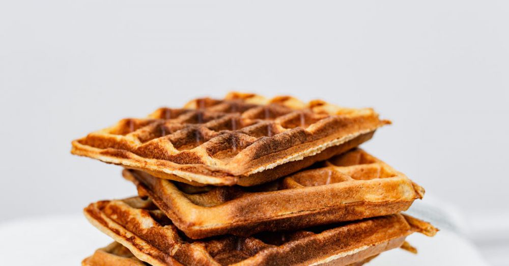 Maple Syrup History - Delicious stack of six crispy homemade waffles on striped white cloth.