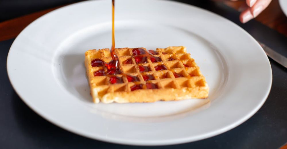 Maple Syrup Benefits - Close-up of a waffle being drizzled with syrup on a white plate, Portugal.