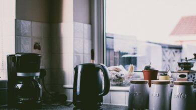 Appliances - Cozy kitchen scene with coffee maker, kettle, and jars on a sunny counter.