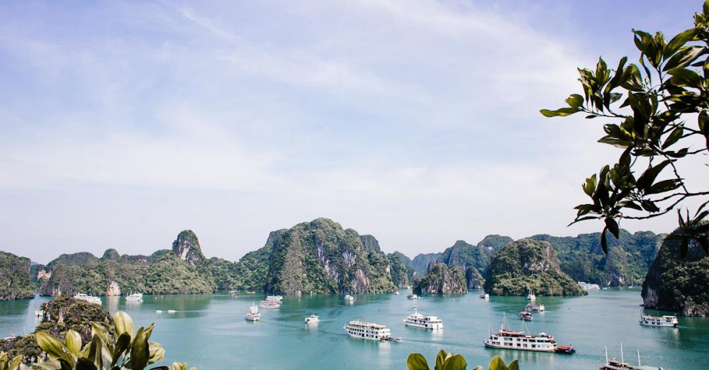 Photography Tours - Serene Halong Bay vista featuring iconic limestone islands and boats under a clear sky.