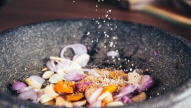 Recipes - Close-up of seasoning being added to fresh ingredients in a stone bowl, perfect for culinary themes.