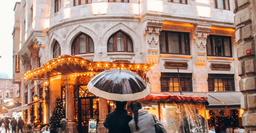 Historical Tour - Couple stands under umbrella in charming European street, festive lights glow.