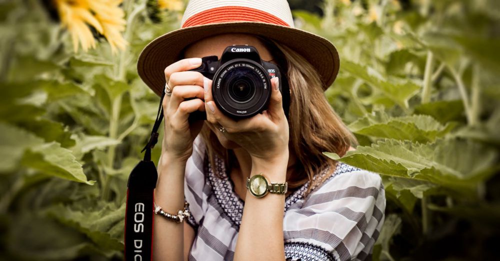 Photography - Woman with hat photographing sunflowers in a summer field using a Canon camera.