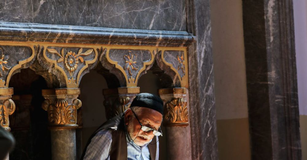 Learning Sites - An elderly man reading in a beautifully ornate Konya mosque, bathed in warm sunlight.