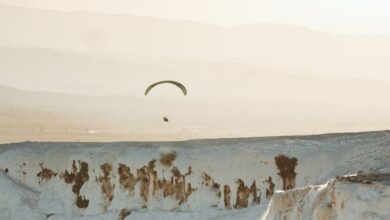 Hot Springs - A paraglider soars above the stunning white terraces of Pamukkale at sunset.