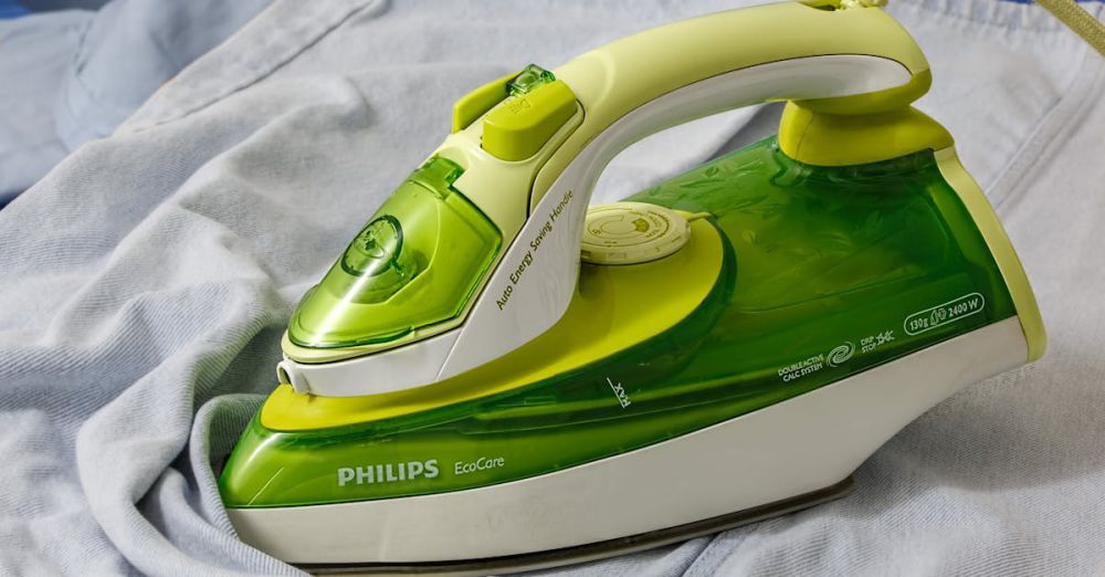 Appliances - Green Philips EcoCare iron on a wrinkled shirt, ready for ironing.