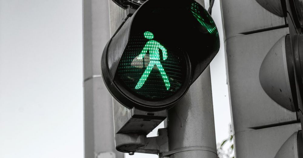 Safety - Close-up of a green pedestrian traffic signal indicating walk at an intersection.