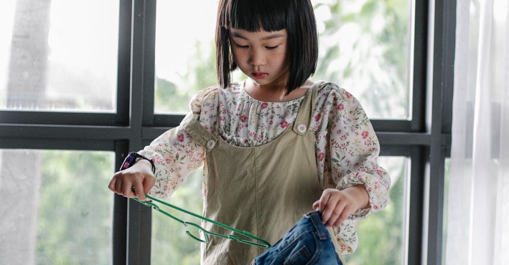 Family Springs - Concentrated child in casual clothes standing near table full of various garments and doing cleaning