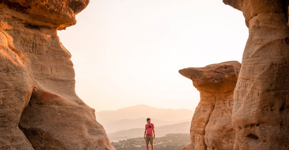 Hiking And Springs - Hiker stands between scenic rock formations at sunset in Colorado Springs.