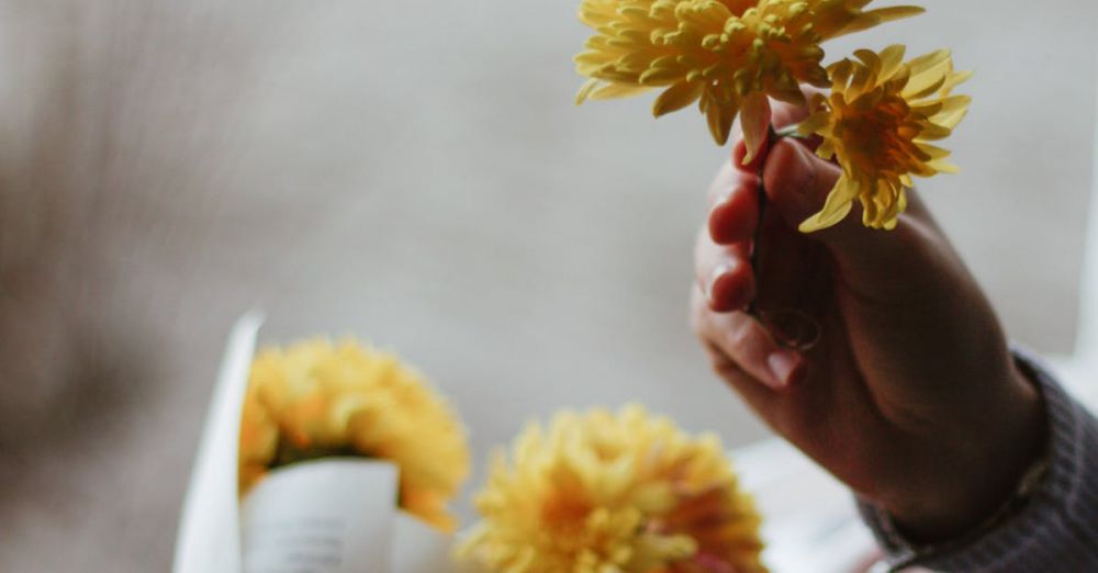 Private Springs - Crop anonymous person with blossoming yellow flowers above windowsill with striped fabric in light house