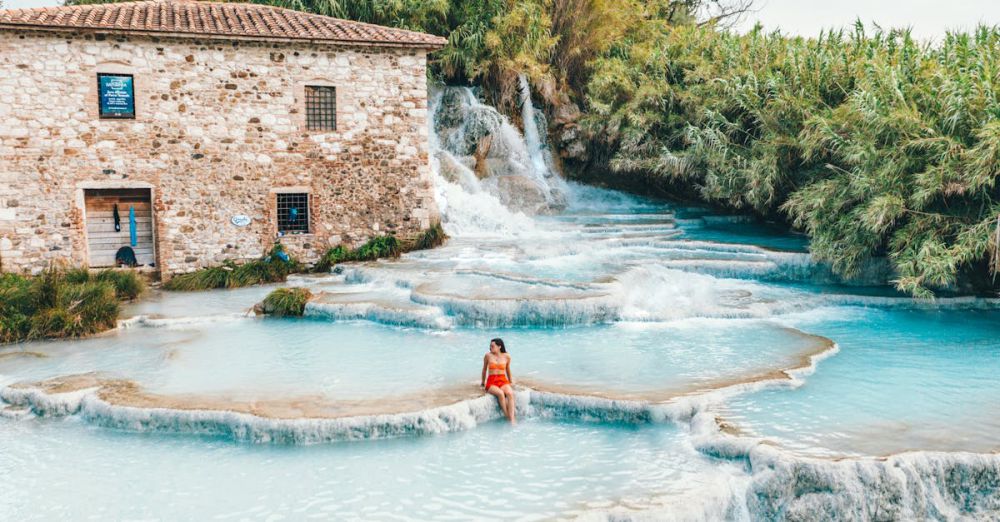 Healing Springs - A woman relaxing at the scenic Cascate del Mulino hot springs in Tuscany, Italy.