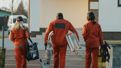 Vacuum Cleaners - Cleaning crew in red uniforms with equipment approaching a modern house exterior.